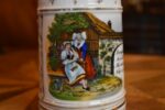 Starožitný žertovný porcelánový půllitr s výjevem z Prodané nevěsty a prolamovaným okrajem.